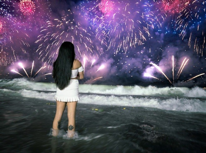 Mulher observa o espetáculo dos fogos em Copacabana. A queima de fogos foi em dez balsas ancoradas ao longo da orla. Foto de Léo Martins