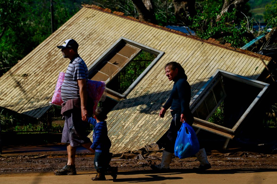 Pessoas passam por uma casa danificada por um ciclone em Muçum, Rio Grande do Sul