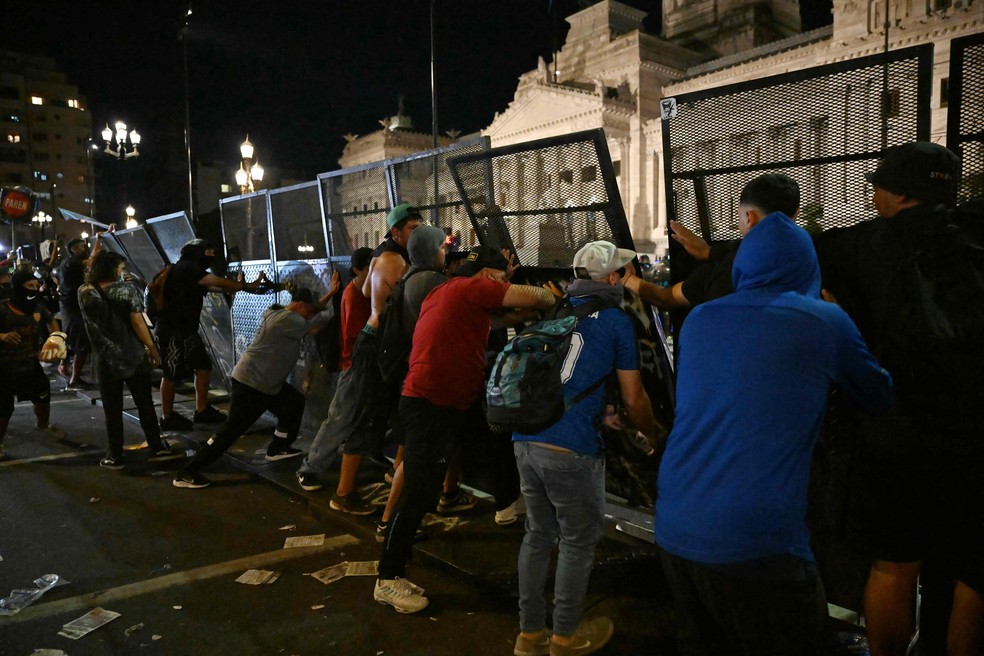 Durante protesto em frente ao Congresso Nacional, em Buenos Aires, manifestantes tentam derrubar grades de proteção da polícia — Foto: Luis ROBAYO / AFP