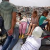 Crianças deslocadas de Rafah sentadas em cima dos seus pertences em Khan Yunis - Bashar TALEB / AFP