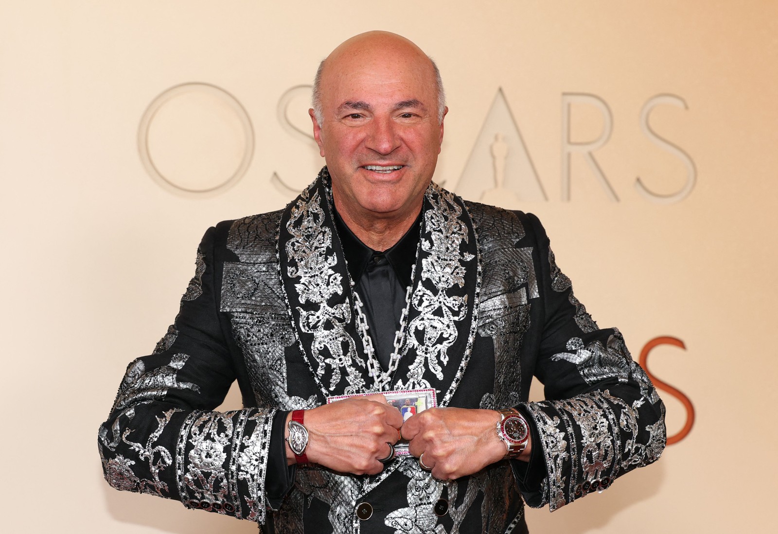 O empresário Kevin O'Leary ajeita um colar cravejado de diamantes com um raro cartão colecionável “Logoman” de basquete, com pedaços de camisas usadas em jogos e autógrafos de Michael Jordan e Kobe Bryant, enquanto se prepara para as fotos no tapete vermelho — Foto: ANGELA WEISS/AFP