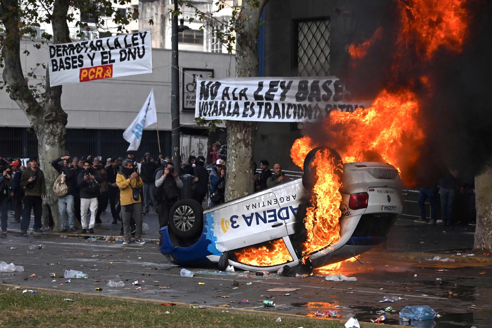 m carro da estação de rádio Cadena 3 incendiado é retratado durante um protesto em frente ao Congresso Nacional em Buenos Aires — Foto: Luis ROBAYO / AFP