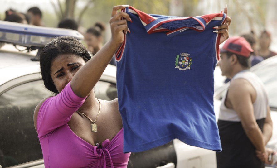 Manifestante chora ao segurar o uniforme de Dijalma de Azevedo, de 11 anos, morto por bala perdida