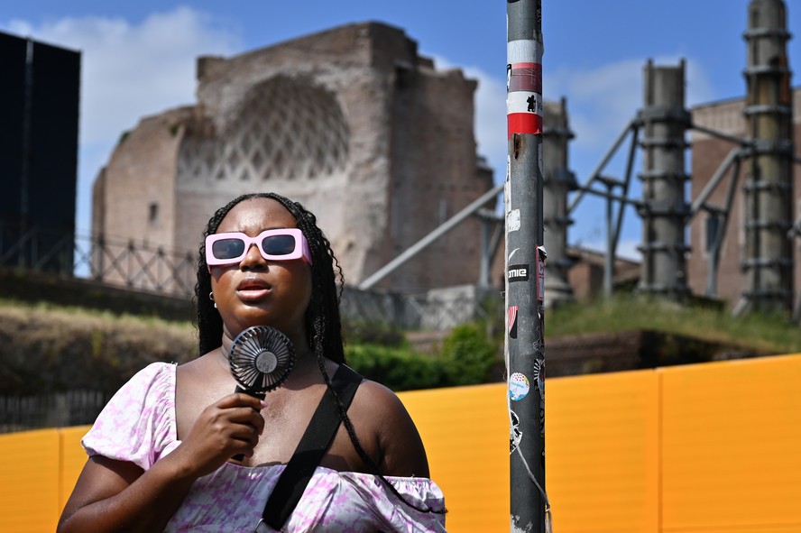 Uma mulher se refresca com um miniventilador em Roma, em 14 de julho de 2023, enquanto a Itália é atingida por uma onda de calor