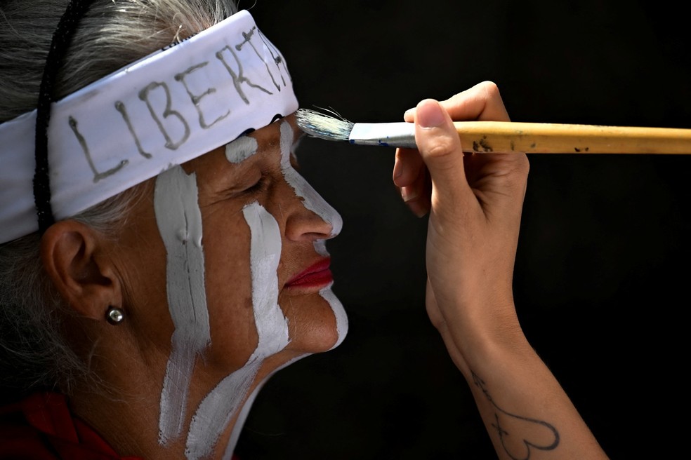 Uma mulher tem o rosto pintado durante um protesto em frente à sede das Nações Unidas em Caracas, em 18 de fevereiro de 2026 — Foto: JUAN BARRETO / AFP