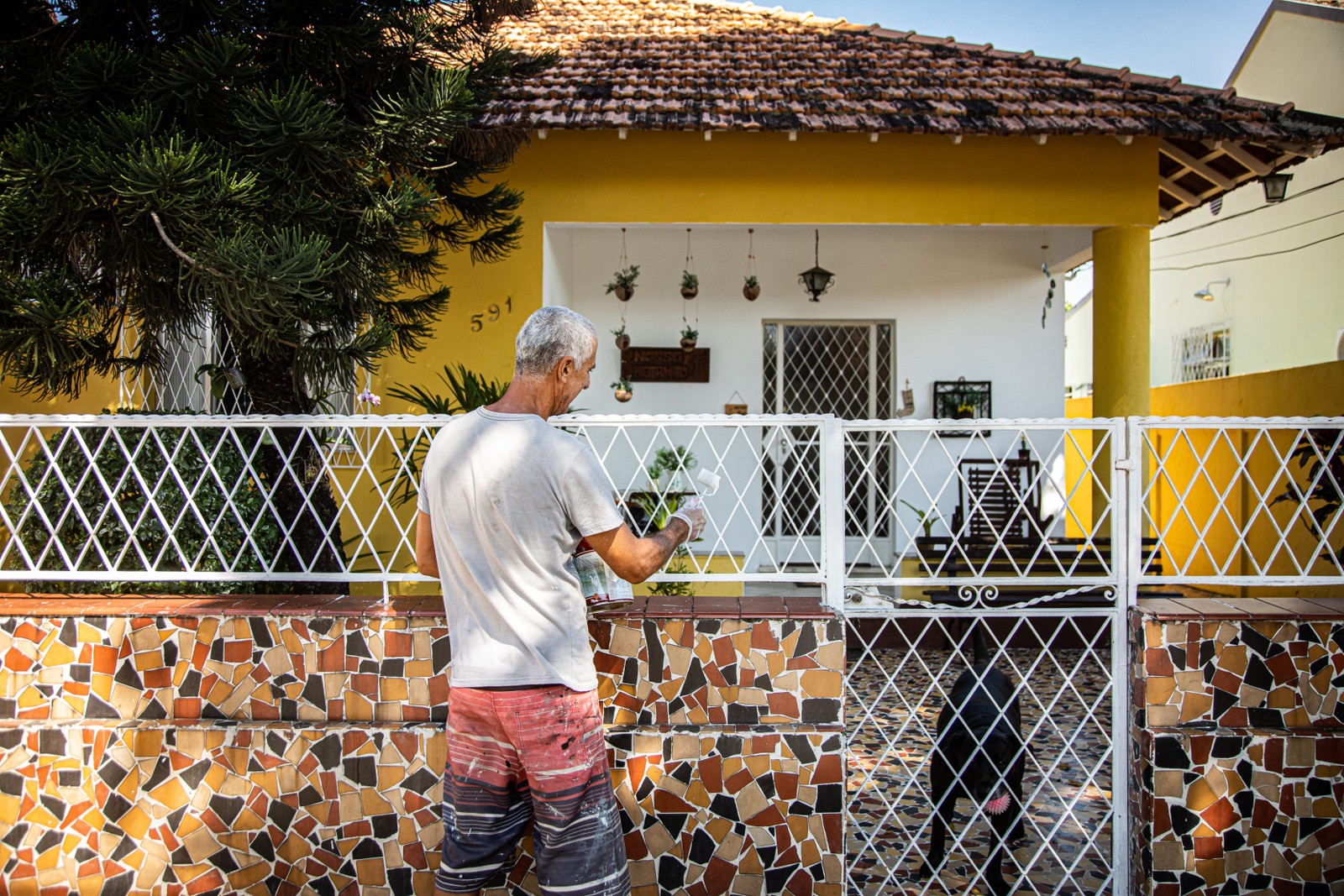 Leonardo paints a fence on the wall of the house which served as a setting for soap operas, films, series and advertisements — Photo: Hermes de Paula / Agência O Globo