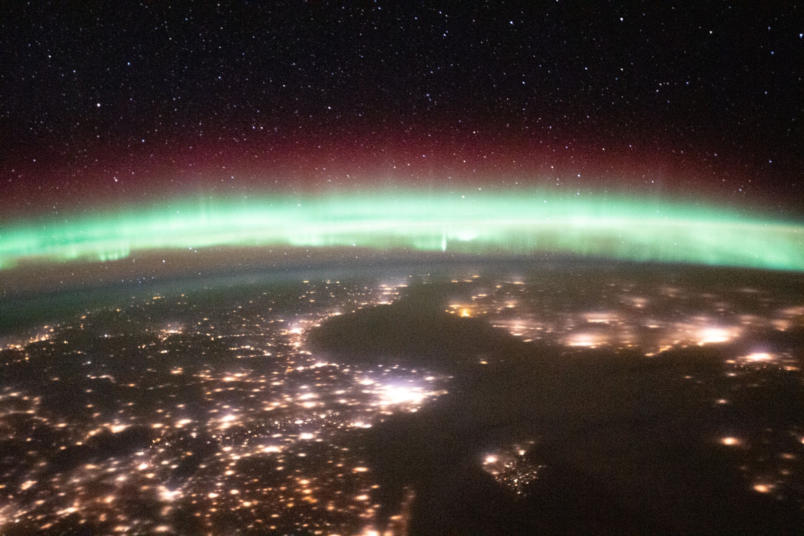 Suécia e Finlândia, com o Mar Báltico entre elas, vistas à noite com uma aurora acima do horizonte da Terra em registro da Estação Espacial Internacional, a cerca de 420 quilômetros acima da Romênia, datado de 18 de janeiro de 2021