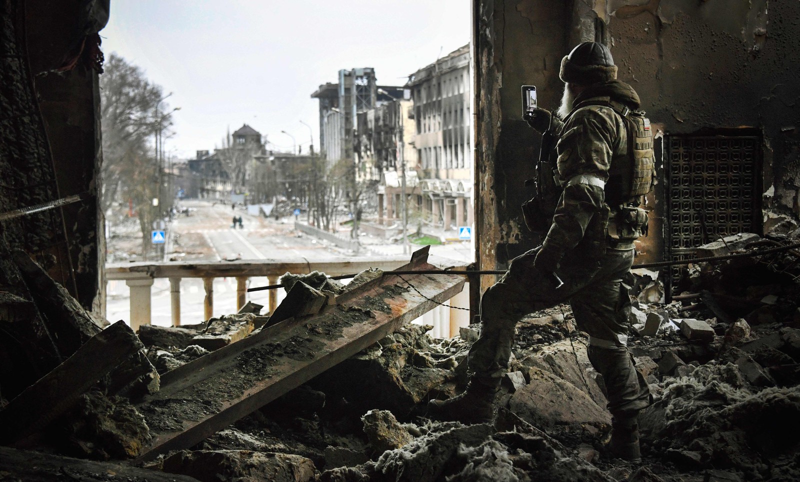 Soldado russo patrulha, em 12 de abril, o teatro dramático de Mariupol, bombardeado em 16 de março, enquanto as tropas russas intensificam uma campanha para tomar a estratégica cidade portuária. — Foto: Alexander NEMENOV / AFP