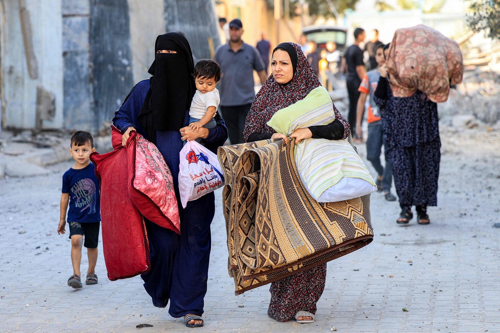 Mulheres palestinas caminham com crian&ccedil;as e pertences enquanto fogem de uma &aacute;rea ap&oacute;s ataque a&eacute;reo israelense em Rafah, no sul da Faixa de Gaza &mdash; Foto: SAID KHATIB/AFP