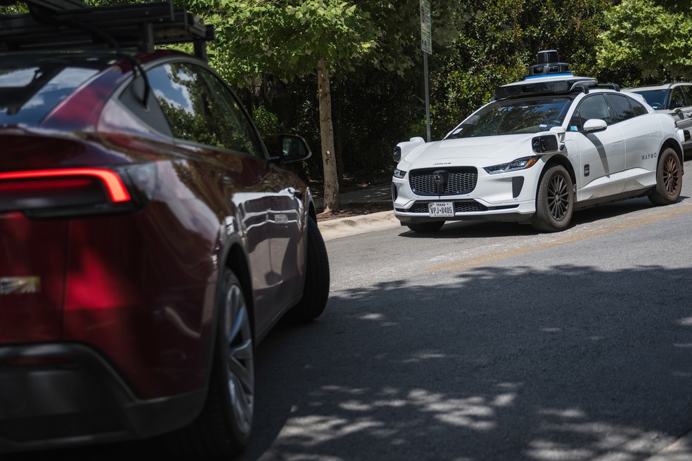 Um táxi autônomo da Waymo, à direita, e um veículo que a Tesla está usando para testes de robotáxi são vistos nas ruas de Austin na sexta-feira, 20 de junho — Foto: Bloomberg