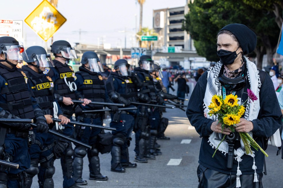 Manifestante carrega flores em frente a policiais em protesto em Los Angeles — Foto: Ringo Chiu/AFP