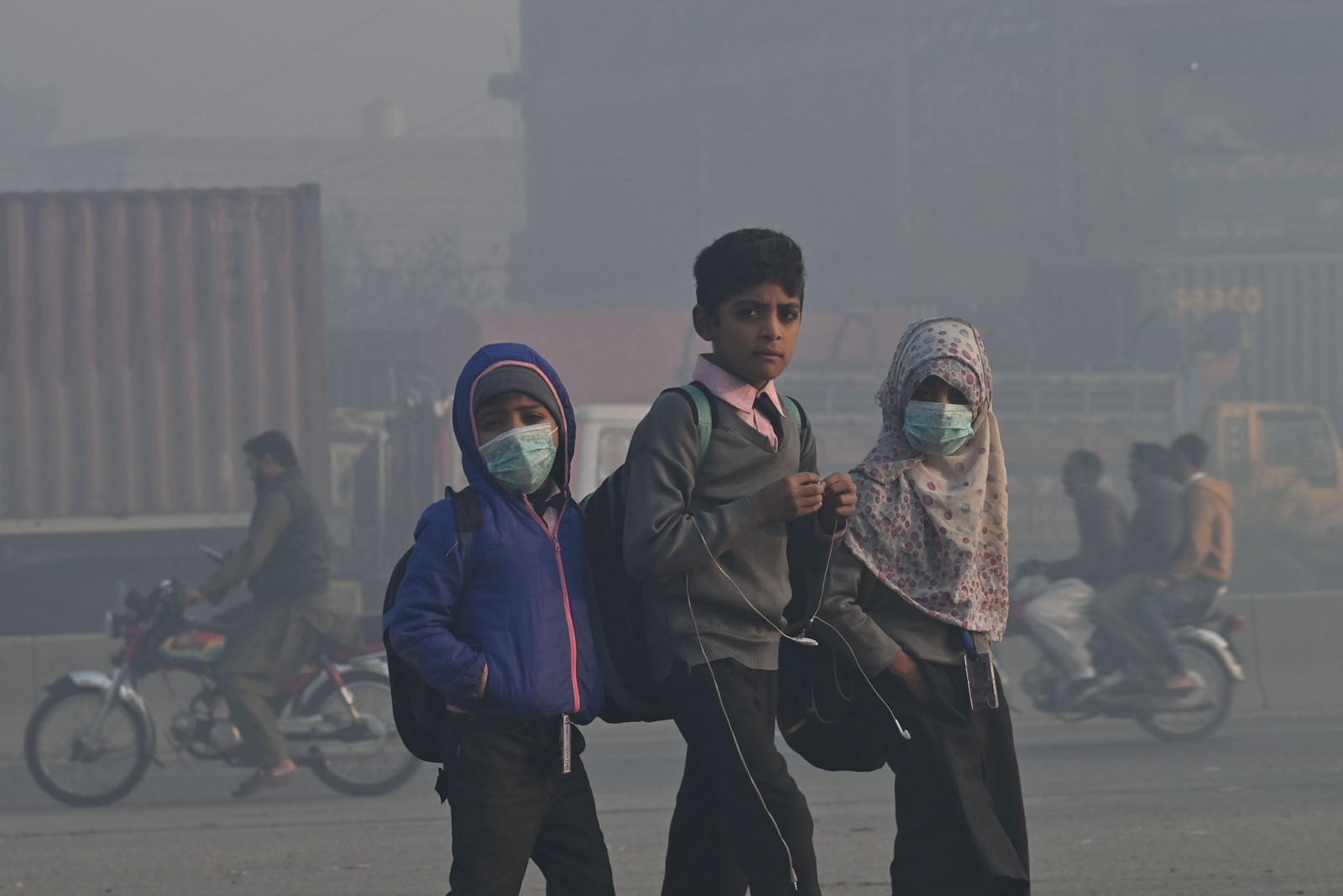 Crianças caminham para a escola em meio a fortes condições de poluição atmosférica em Lahore, Paquistão — Foto: ARIF ALI/AFP