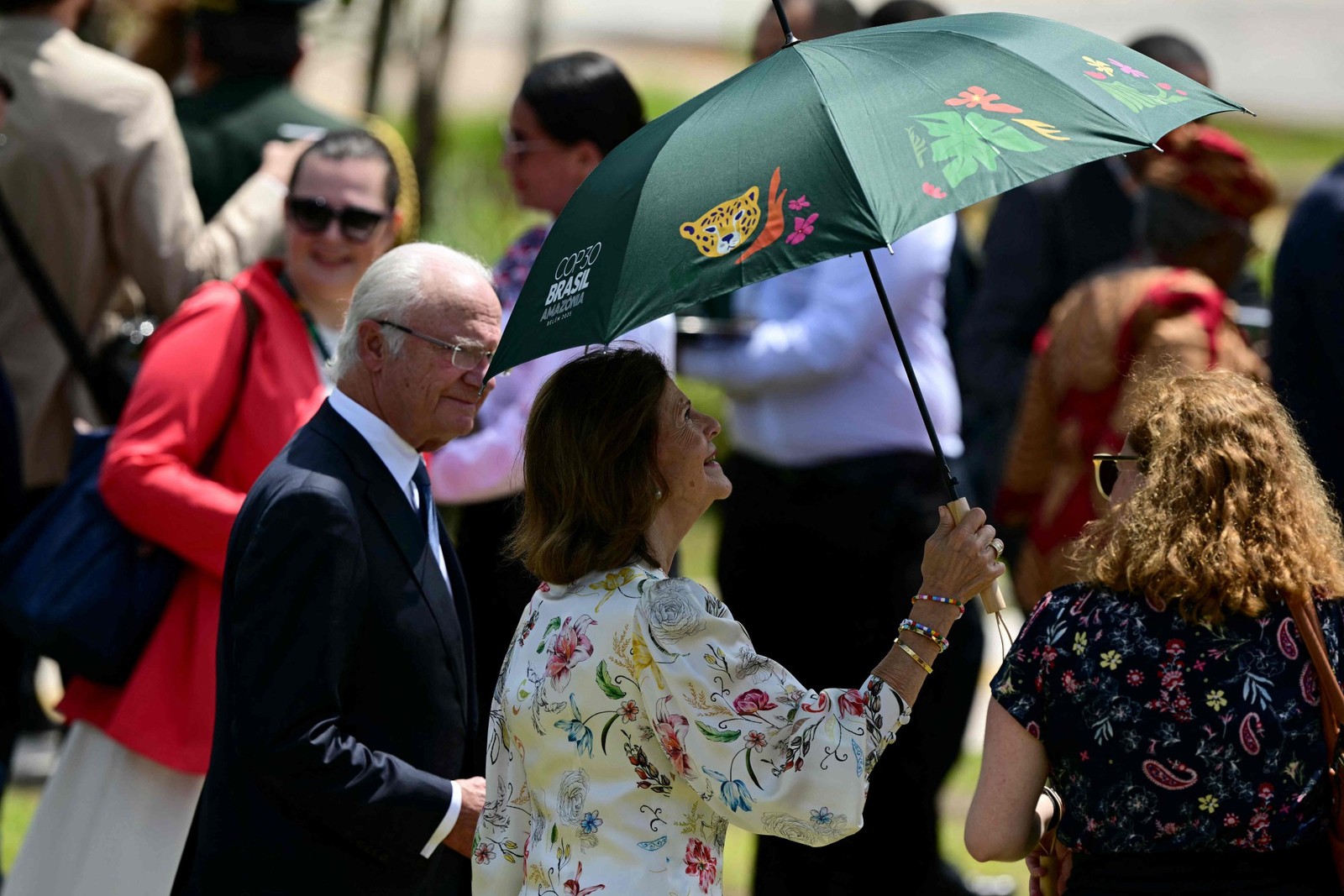 Queen Silvia of Sweden protects herself from the sun before taking part in a COP30 family photo alongside King Carl XVI Gustaf — Photo: Pablo PORCIUNCULA / AFP