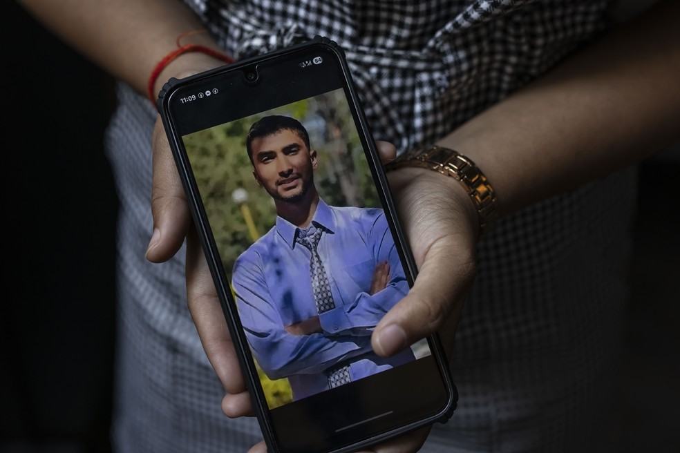 Pushpa Joshi mostra uma foto de seu irmão Bipin Joshi, um estudante nepalês em Israel que foi sequestrado pelo Hamas há quase dois anos — Foto: Dave Sanders/The New York Times