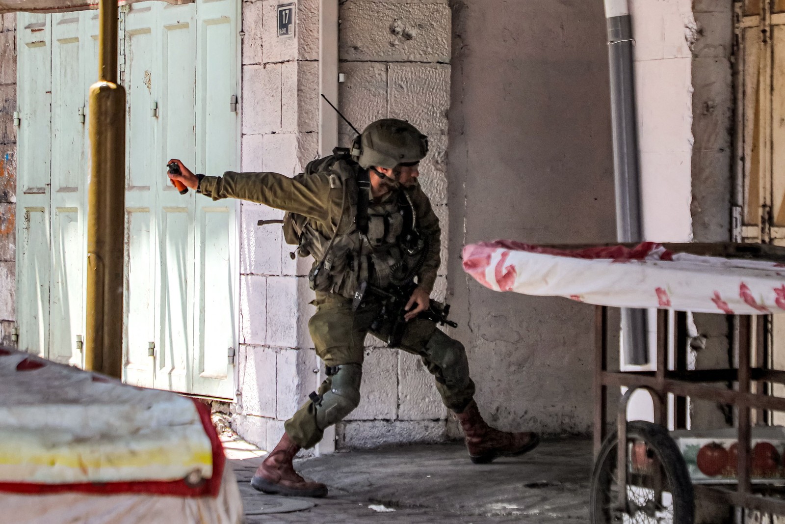 Soldado israelense lança uma granada de controle de distúrbios durante confrontos no centro de Hebron — Foto: MOSAB SHAWER / AFP
