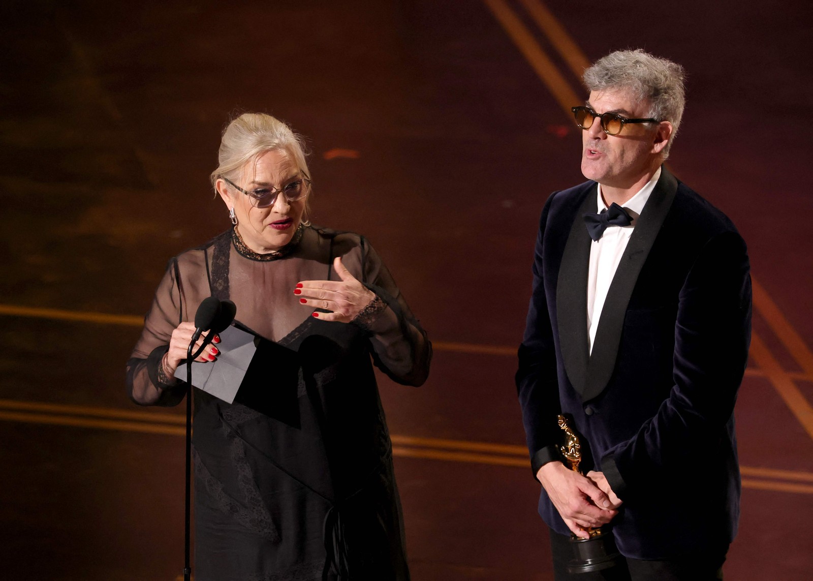 Tamara Deverell e Shane Vieau aceitam o prêmio de Melhor Direção de Arte por “Frankenstein”. — Foto: KEVIN WINTER