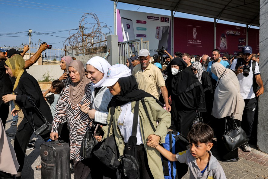 Pessoas atravessam um portão para entrar na passagem de fronteira de Rafah para o Egito, no sul da Faixa de Gaza