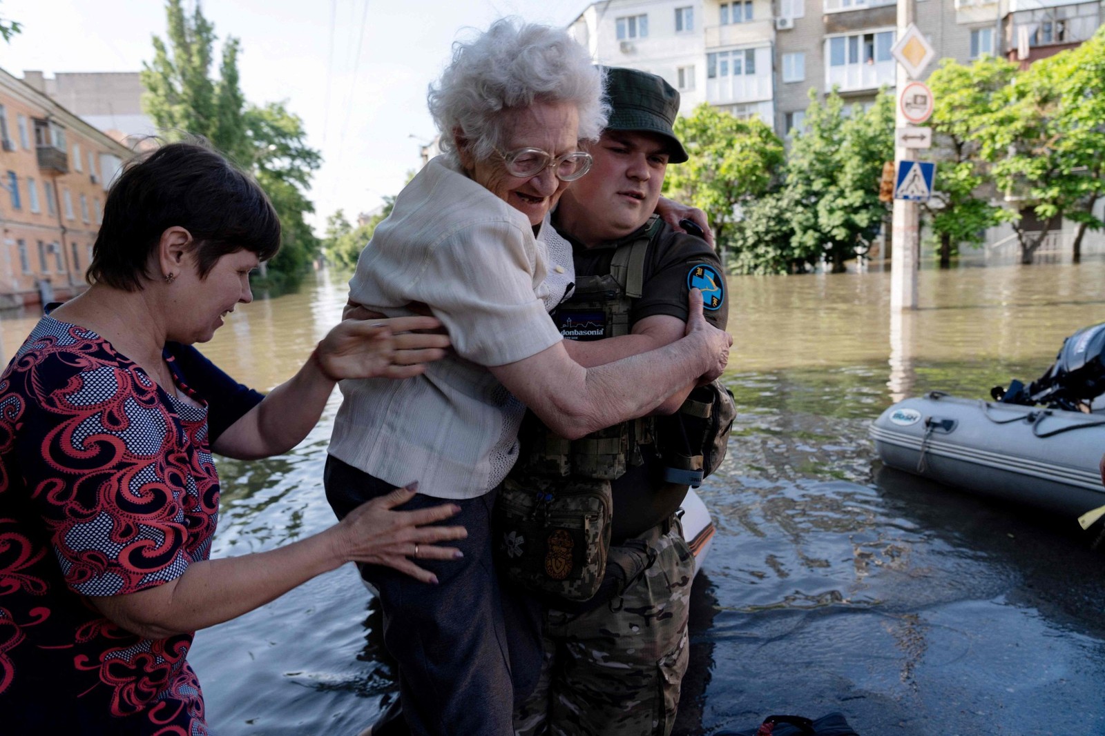 Soldado ucraniano ajuda moradora de Kherson a deixar área alagada após destruição da barragem de Nova Kakhova — Foto: ALEKSEY FILIPPOV / AFP