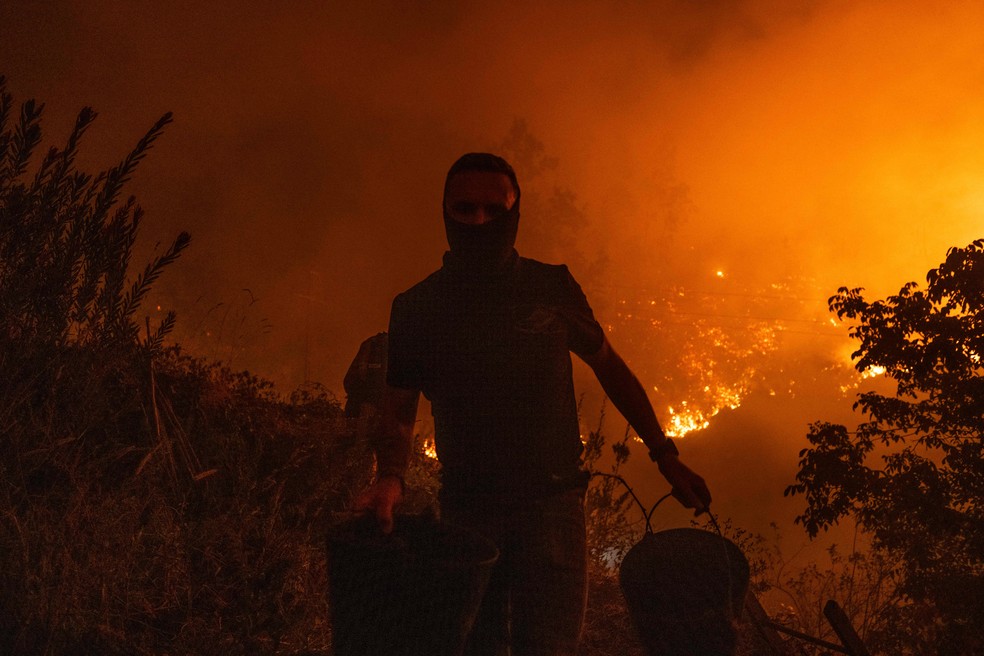 Homem tenta combater o fogo em Albergaria-a-Velha, em Aveiro — Foto: Patrícia de Melo Moreira/AFP