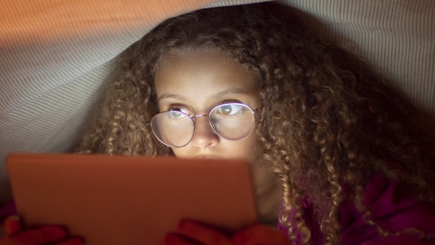 Menina de óculos olha tela de tablet