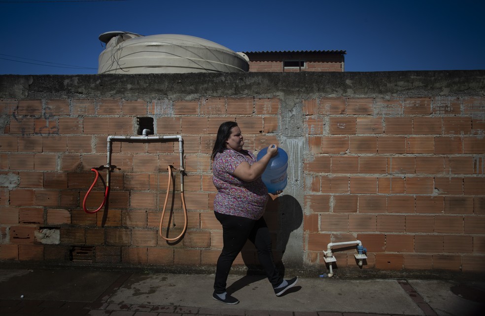 Na terra dos royalties. Gabriela Cristina Santos carrega galão abastecido em caixa d’água pública no bairro Lagomar — Foto: Márcia Foletto/Agência O Globo