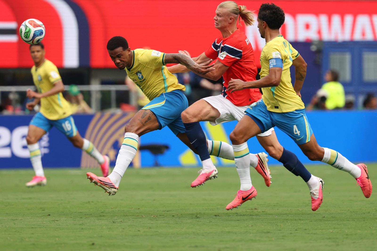 Erling Haaland, Gabriel Magalhães e Marquinhos correm para disputarem a bola — Foto: Odd ANDERSEN / AFP