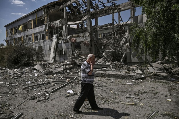 Pessoa caminha em frente a uma escola que foi bombardeada na cidade de Bakhmut, na Ucrânia