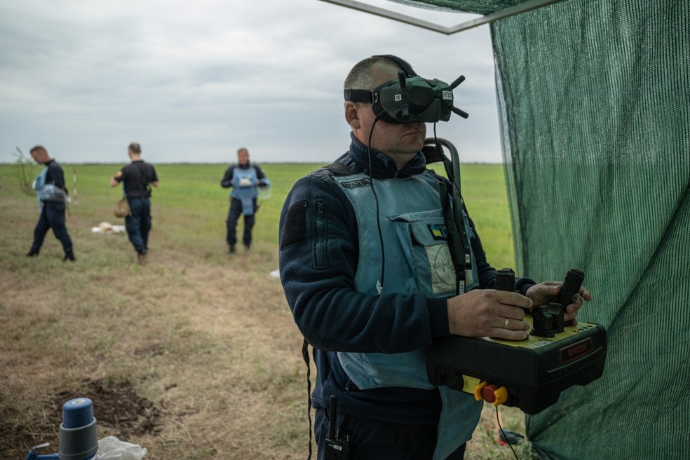 Membros de ONG usam equipamentos para desminagem na Ucrânia — Foto: AFP