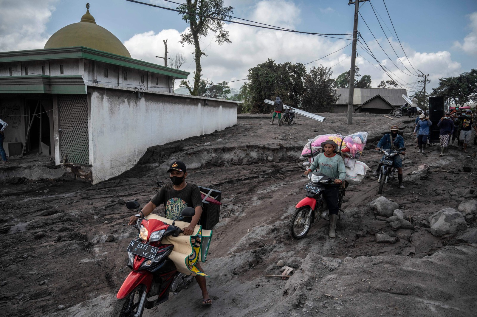 Pessoas resgatam pertences após erupção vulcânica do Monte Semeru, na vila de Kajar Kuning, em Lumajang, Indonésia — Foto: JUNI KRISWANTO/AFP
