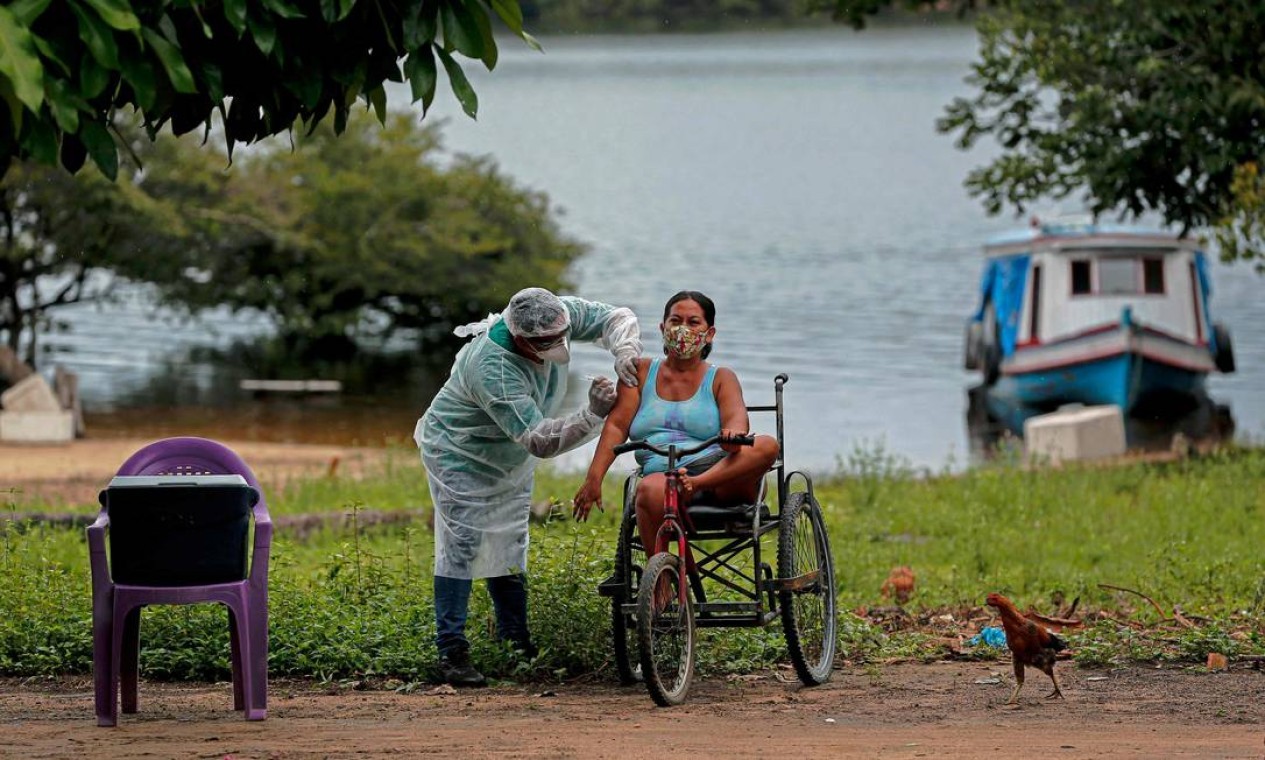 Profissional de saúde da Secretaria de Saúde Indígena do Ministério da Saúde administra uma segunda dose da vacina contra COVID-19 a uma mulher da aldeia Esperança do Rio Arapiun, no Baixo Amazonas, estado do Pará, próximo a Santarém — Foto: TARSO SARRAF / AFP