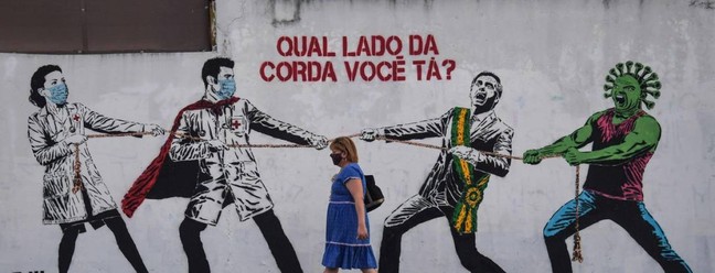 Um grafite representando o presidente Jair Bolsonaro e o novo coronavírus contra profissionais de saúde, em São Paulo — Foto: NELSON ALMEIDA / AFP