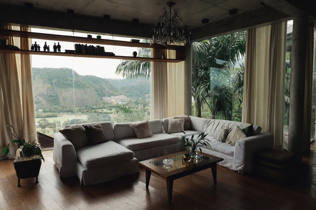 A sala ampla tem janelões que permitem apreciar a vista — Foto: Reprodução/Airbnb