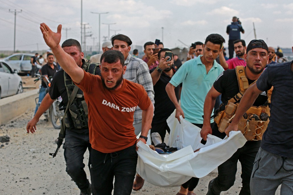 Militantes palestinos carregam uma vítima após um ataque aéreo israelense na passagem de Erez entre Israel e o norte da Faixa de Gaza – BASHAR TALEB / AFP