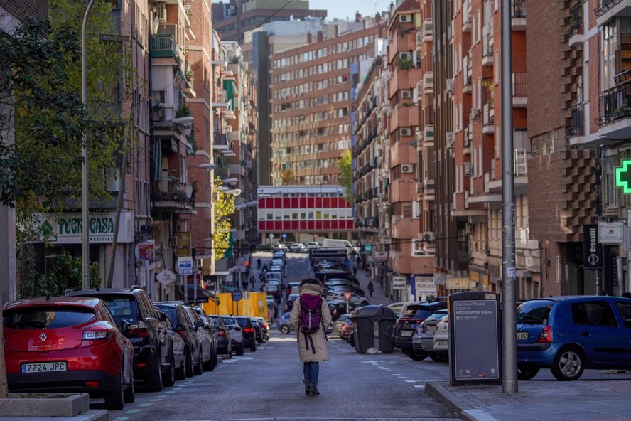 Pedestre caminha por rua residencial em Madri, Espanha
