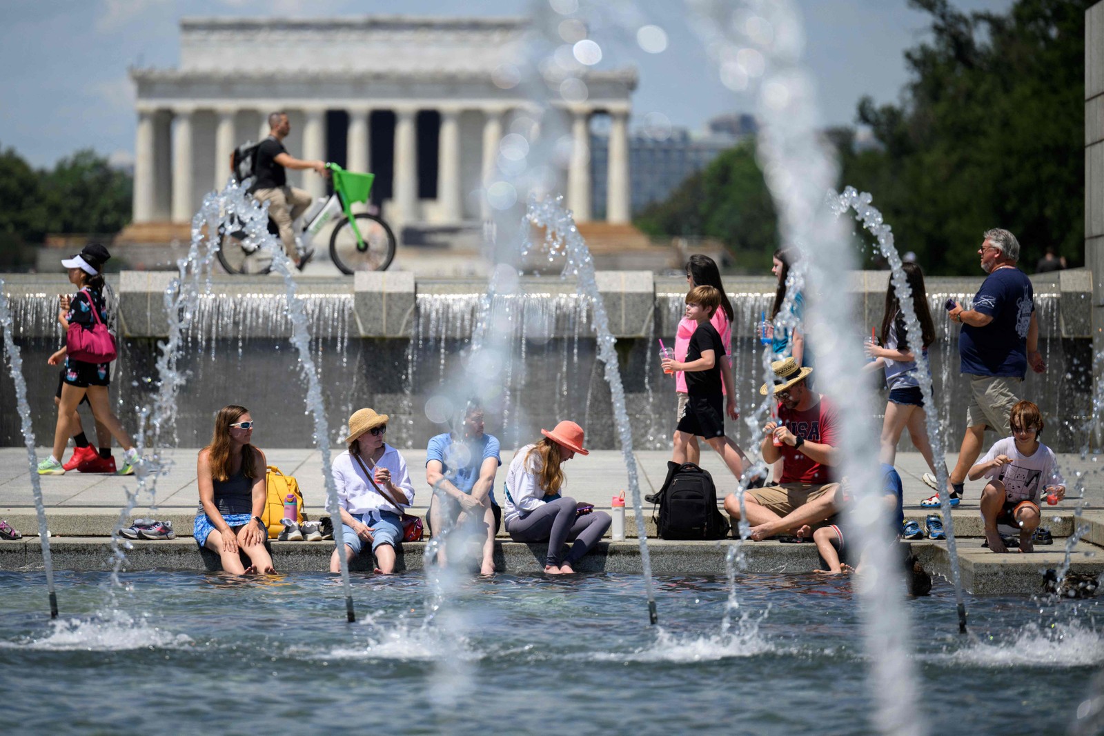 As pessoas colocaram os pés na água para se refrescarem no Memorial da Segunda Guerra Mundial dos EUA, em Washington, DC — Foto: Drew ANGERER / AFP