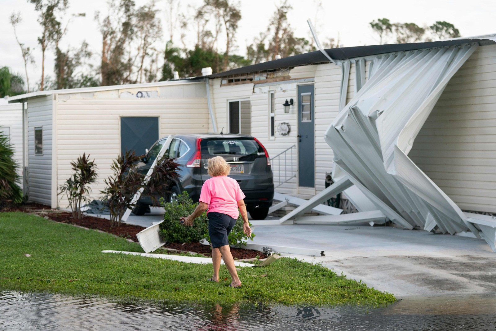 Mulher passa por casa atingida por tempestade após a passagem do Furacão Milton, em 10 de outubro de 2024, em Osprey, Flórida — Foto: Sean Rayford / Getty Images / AFP
