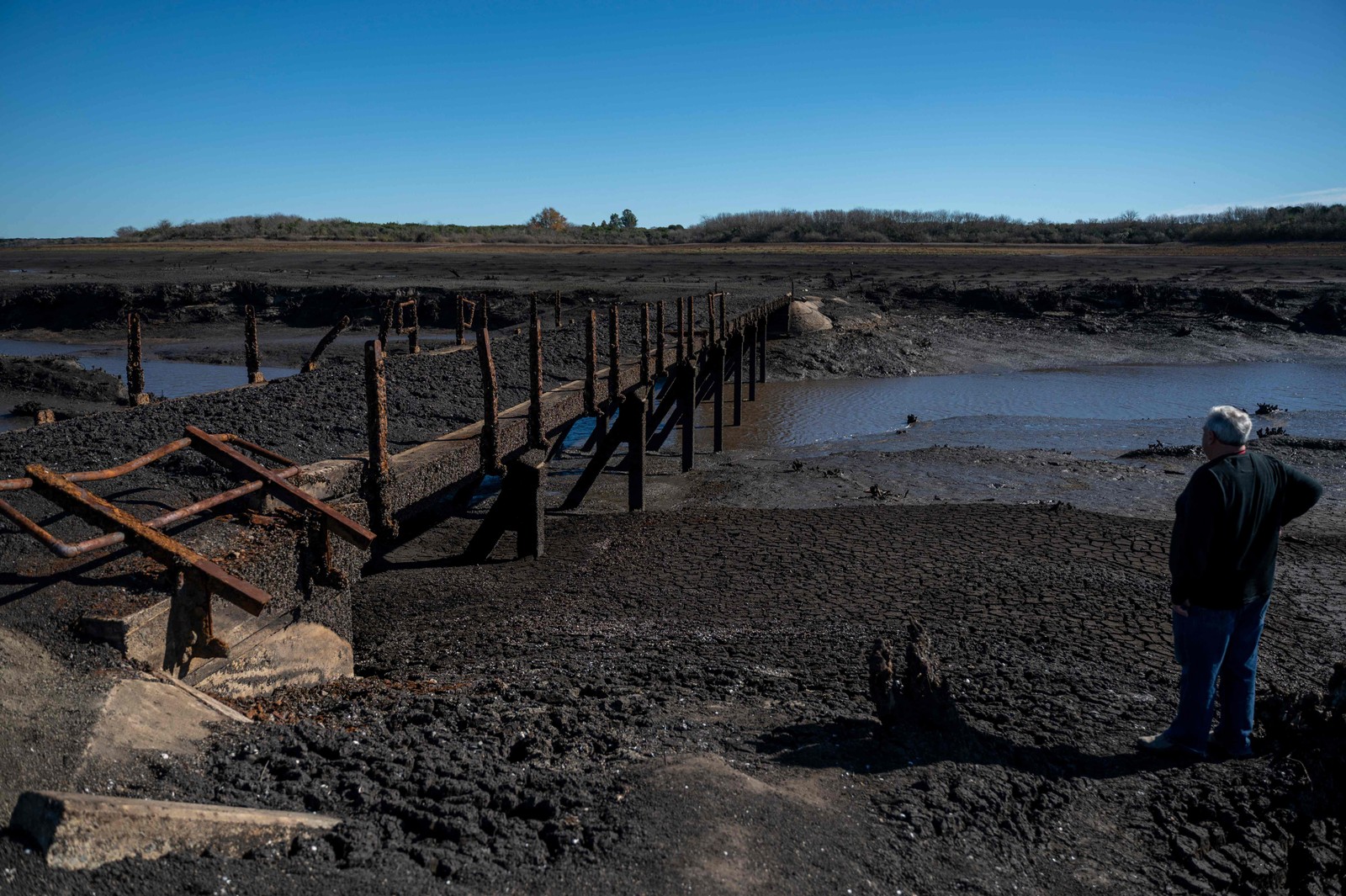 O uruguaio Raul Damiano olha para ponte que emergiu sob o reservatório de Paso Severino em meio a uma seca — Foto: Eitan ABRAMOVICH / AFP