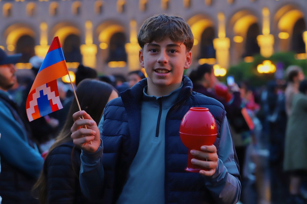 Jovem armênio segura vela e bandeira da República de Artsakh (Nagorno-Karabakh) em marcha em memória às vítimas do genocídio armênio, em Erevan — Foto: Davit Hakobyan / União Geral Armênia de Beneficência (UGAB Brasil)
