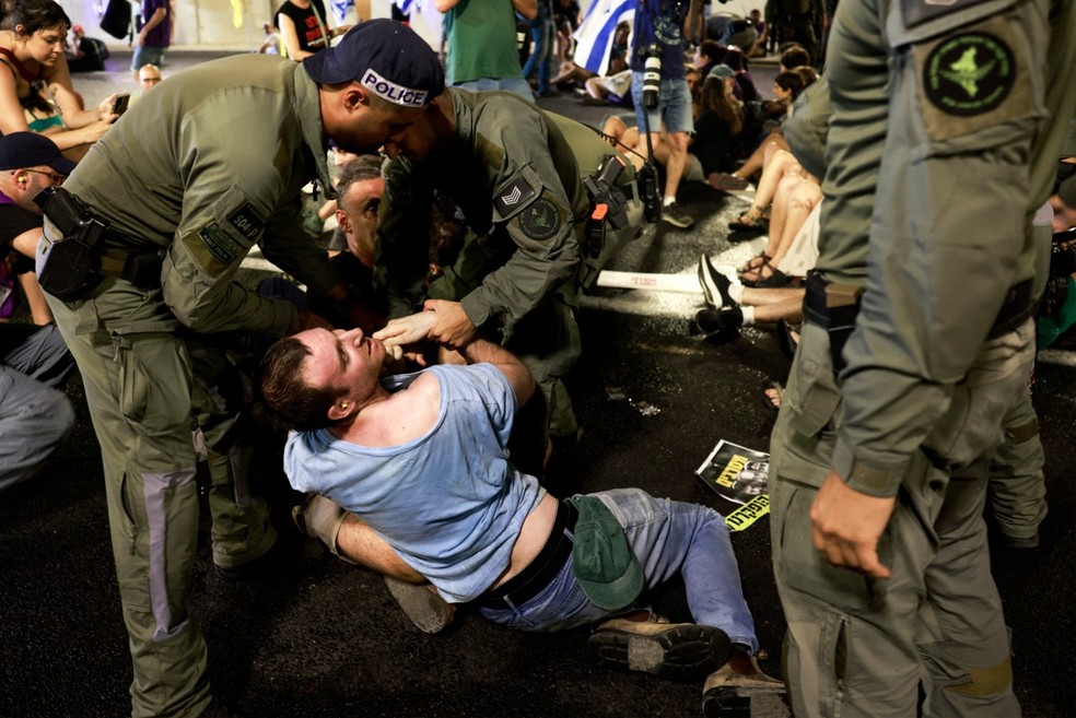Policiais israelenses retiram manifestantes que bloqueavam um túnel durante protesto em Jerusalém, em 17 de agosto de 2025, por um acordo que liberte reféns mantidos pelo Hamas — Foto: Menahem Kahana/AFP