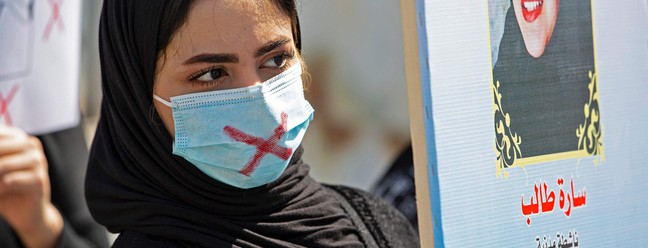 Mulher iraquiana protesta contra o silenciamento, usando máscara riscada, na cidade de Basra, no sul do IraqueAFP