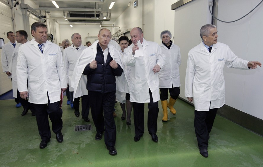 Vladimir Putin (centro-esquerda) conversa com Yevgeny Prigozhin durante visita fábrica de merenda escolar em São Petersburgo
