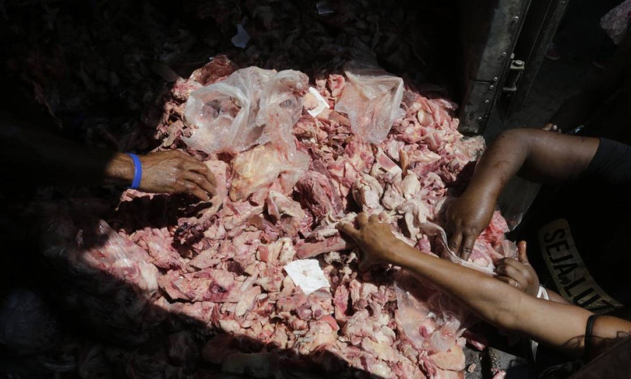 Pessoas selecionam porções do que restou da carne dos mercados. — Foto: Domingos Peixoto / Agência O Globo