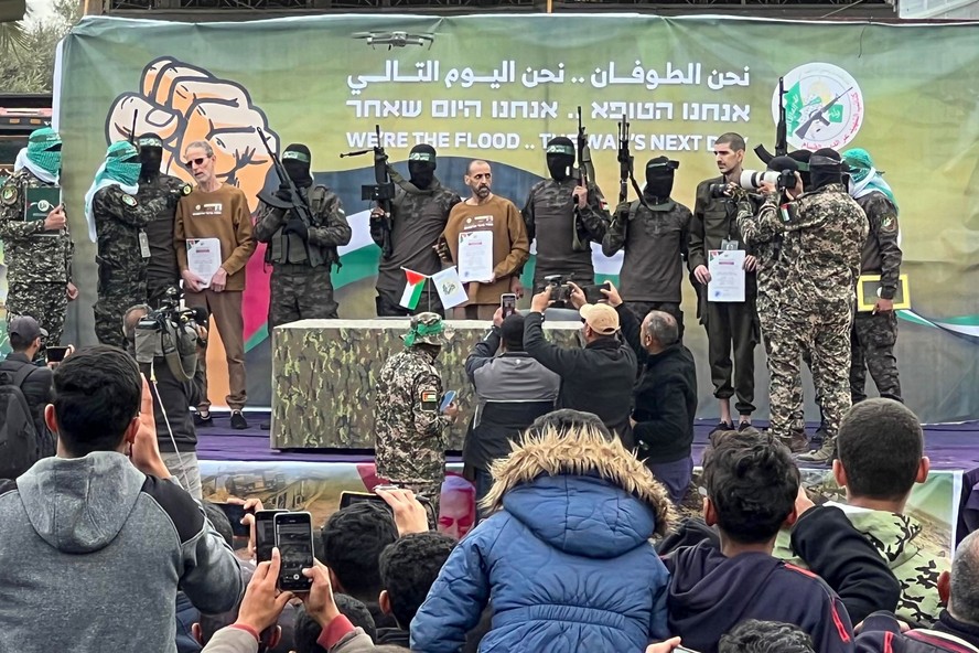 Combatentes do Hamas escoltam os reféns israelenses Or Levy (segundo à esquerda) e Eli Sharabi (segundo à direita) em um palco antes de entregá-los a uma equipe da Cruz Vermelha em Deir el-Balah, em Gaza