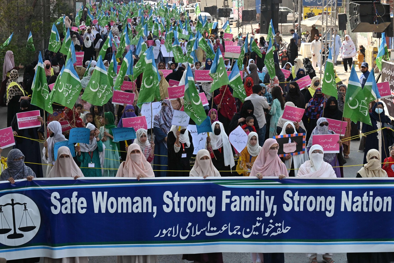 Ativistas do partido Jamaat-e-Islami (JI) seguram cartazes e bandeiras em manifestação pelo Dia Internacional da Mulher, em 2023, em Laore, no Paquistão. Arif Ali / AFP
