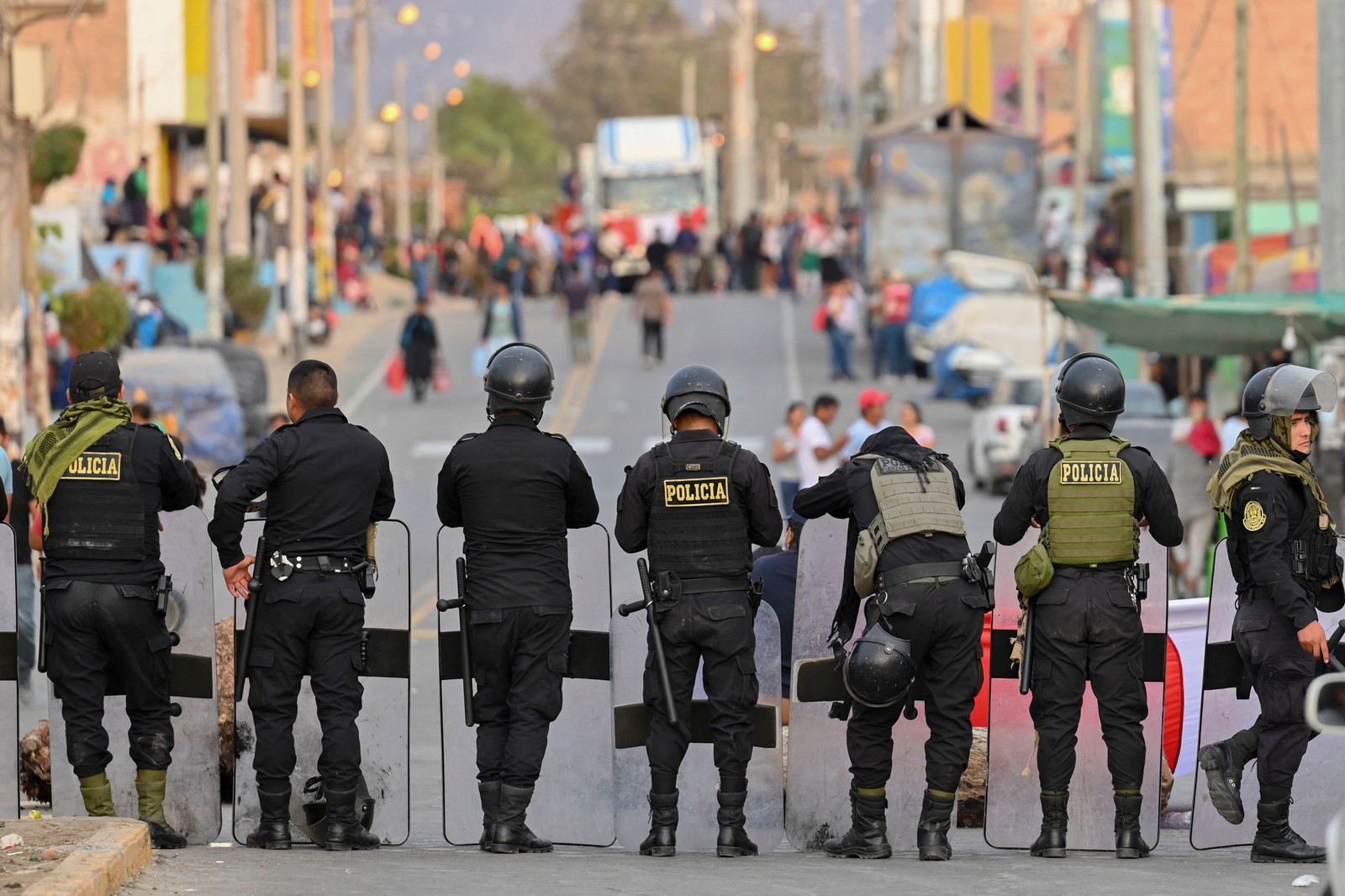 Policiais montam guarda em uma rua de Humay, Peru, depois de deter um comboio de manifestantes Chancas, da região central dos Andes, a caminho de Lima para participar de uma grande protesto contra a presidente Dina Boluarte — Foto: Cris BOURONCLE / AFP