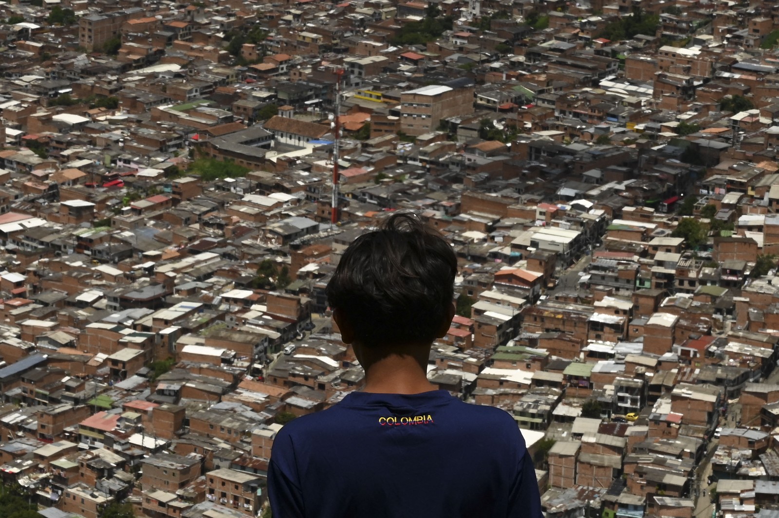 menino olha para a cidade de Medellín de uma favela nos arredores da cidade colombiana. Os candidatos Rodolfo Hernandez, um milionário de 77 anos, e Gustavo Petro, um ex-guerrilheiro de esquerda, enfrentará em um segundo turno para a presidência da Colômbia no próximo domigo (19) — Foto: JOAQUIN SARMIENTO / AFP