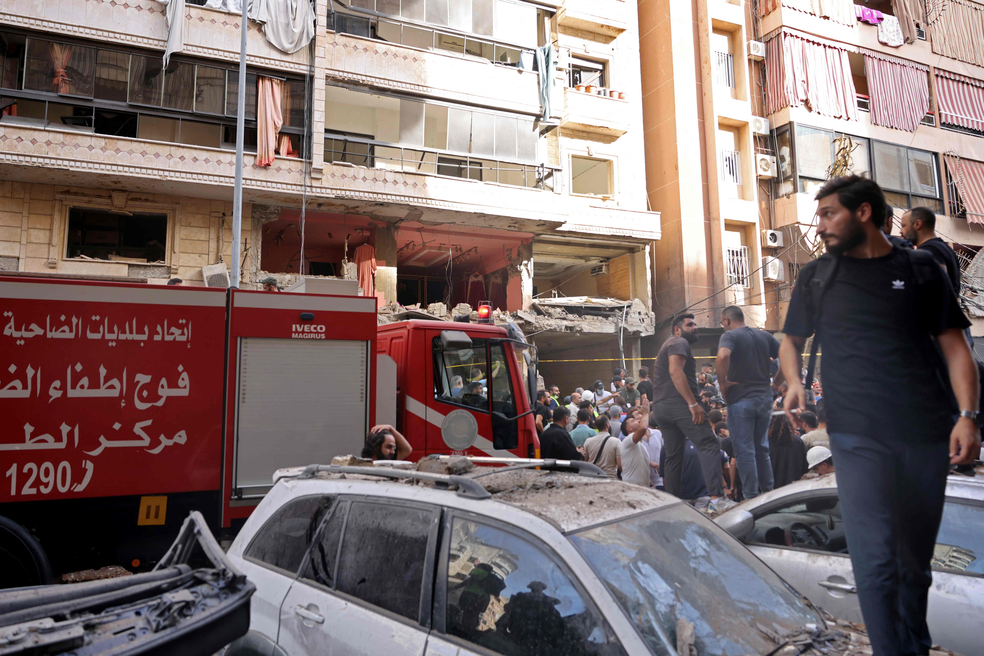 Pessoas e socorristas se reúnem em frente a prédio-alvo de ataque israelense nos subúrbios ao sul de Beirute, no Líbano, em 20 de setembro de 2024 — Foto: Anwar AMRO / AFP
