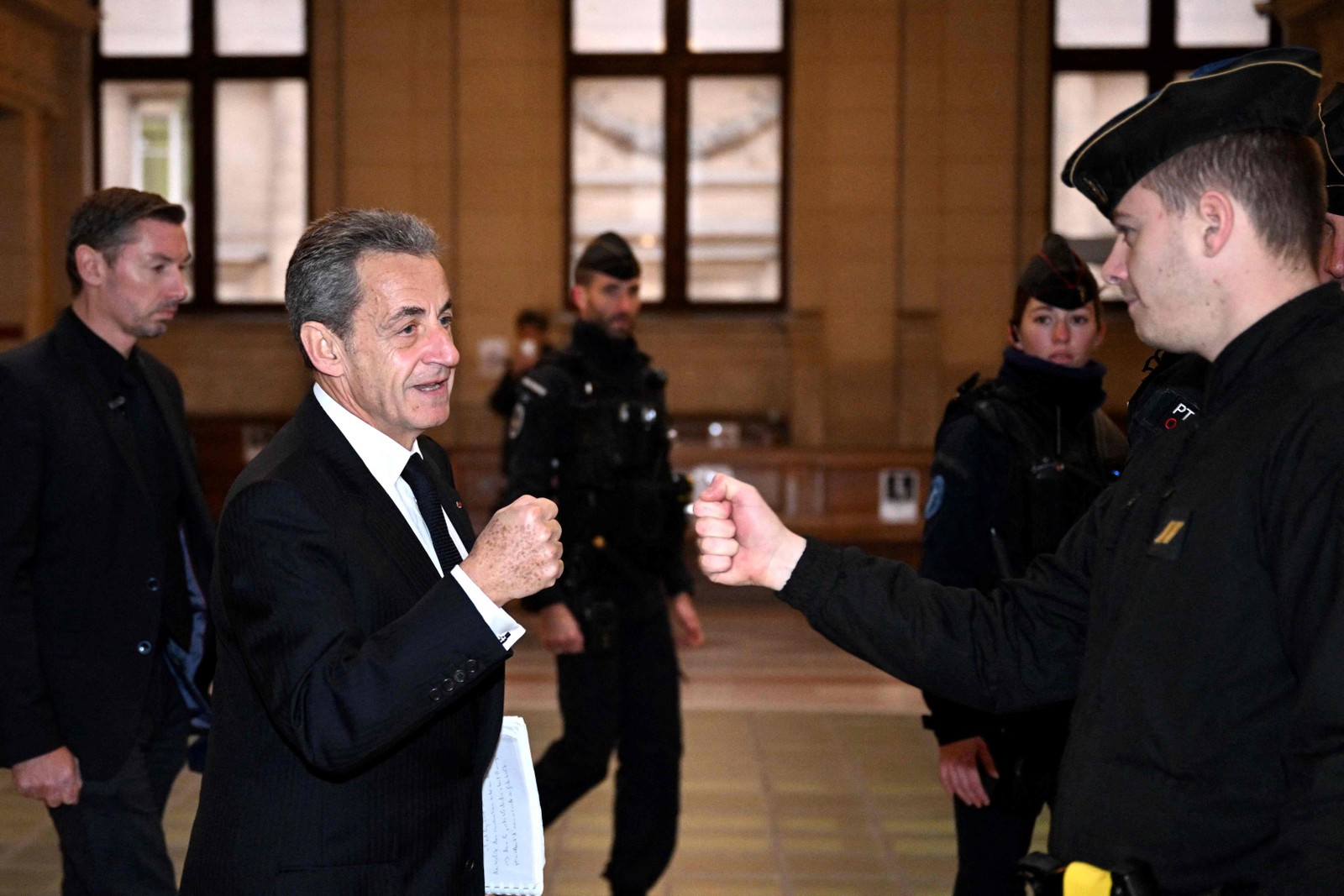Ex-presidente francês Nicolas Sarkozy cumprimenta policial ao chegar ao tribunal no terceiro dia da audiência de apelação do julgamento por corrupção no tribunal de Paris — Foto: EMMANUEL DUNAND/AFP