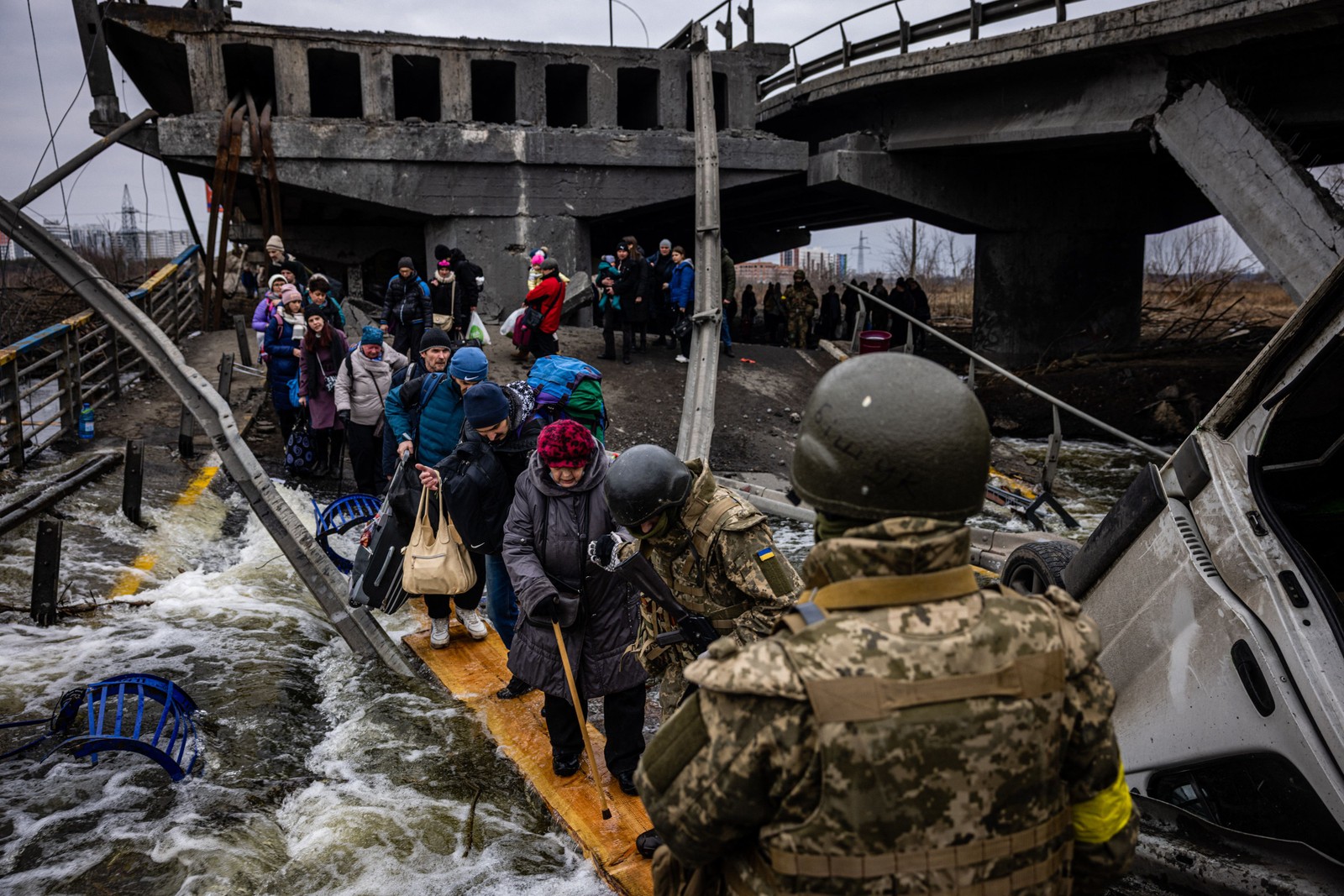 Pessoas atravessam uma ponte destruída enquanto fogem da cidade de Irpin, a noroeste de Kiev, em 7 de março. — Foto: Dimitar DILKOFF / AFP