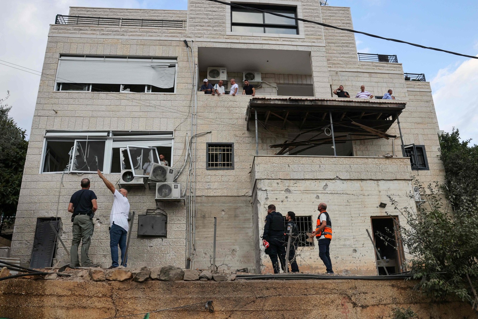 Forças de segurança israelenses inspecionam os danos em um prédio na cidade árabe-israelense de Abu Ghosh, perto de Jerusalém, após ataque do Hamas — Foto: AHMAD GHARABLI / AFP